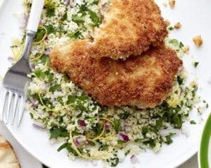 Breaded pork chops on a bed of couscous, on a white plate