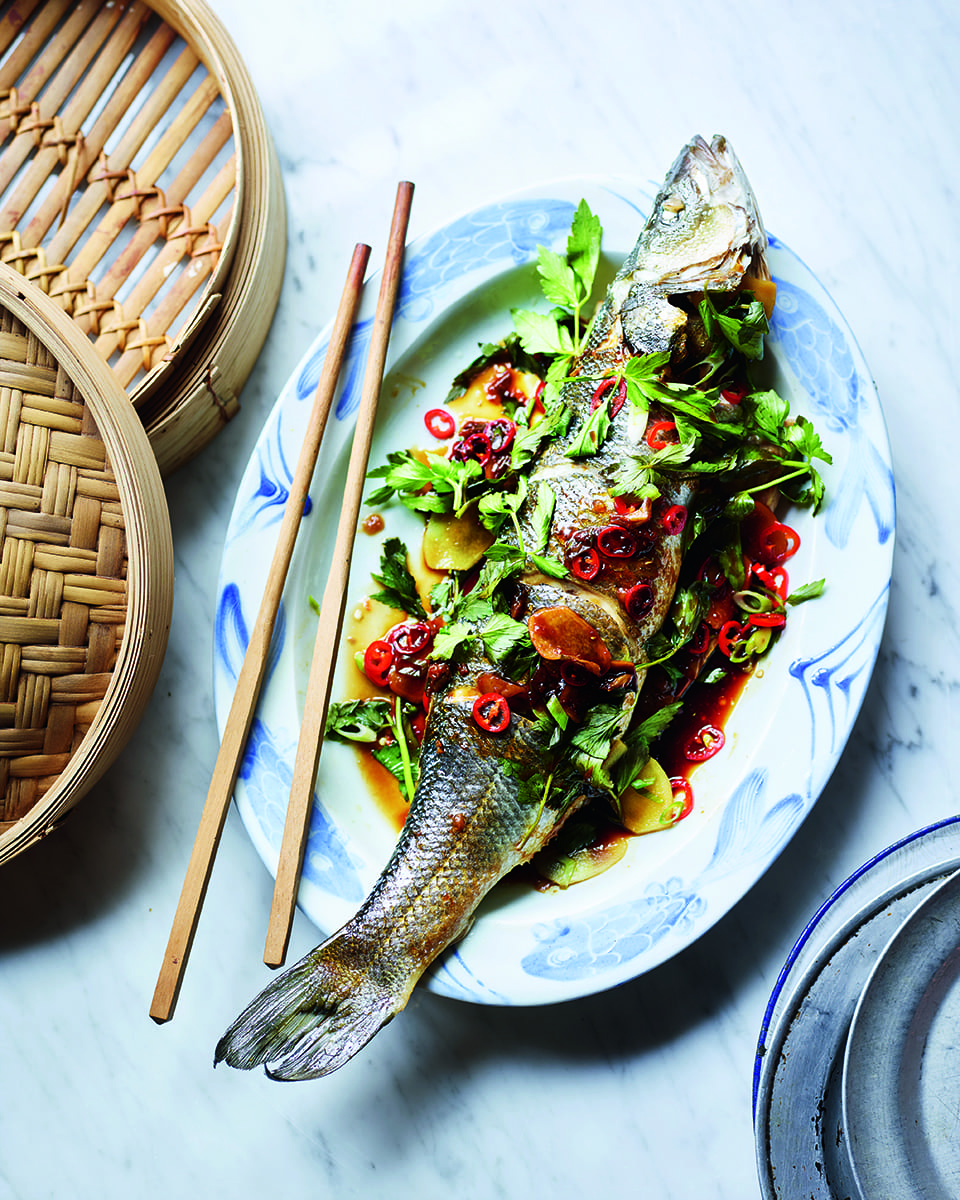 Whole steamed fish shown on a plate with chopsticks